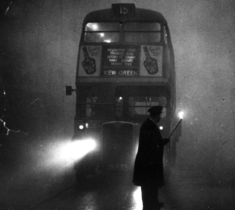 An inspector carrying a flare to guide the driver of a London bus during the Great Smog.  Credit: Alan Farrow; public domain.
