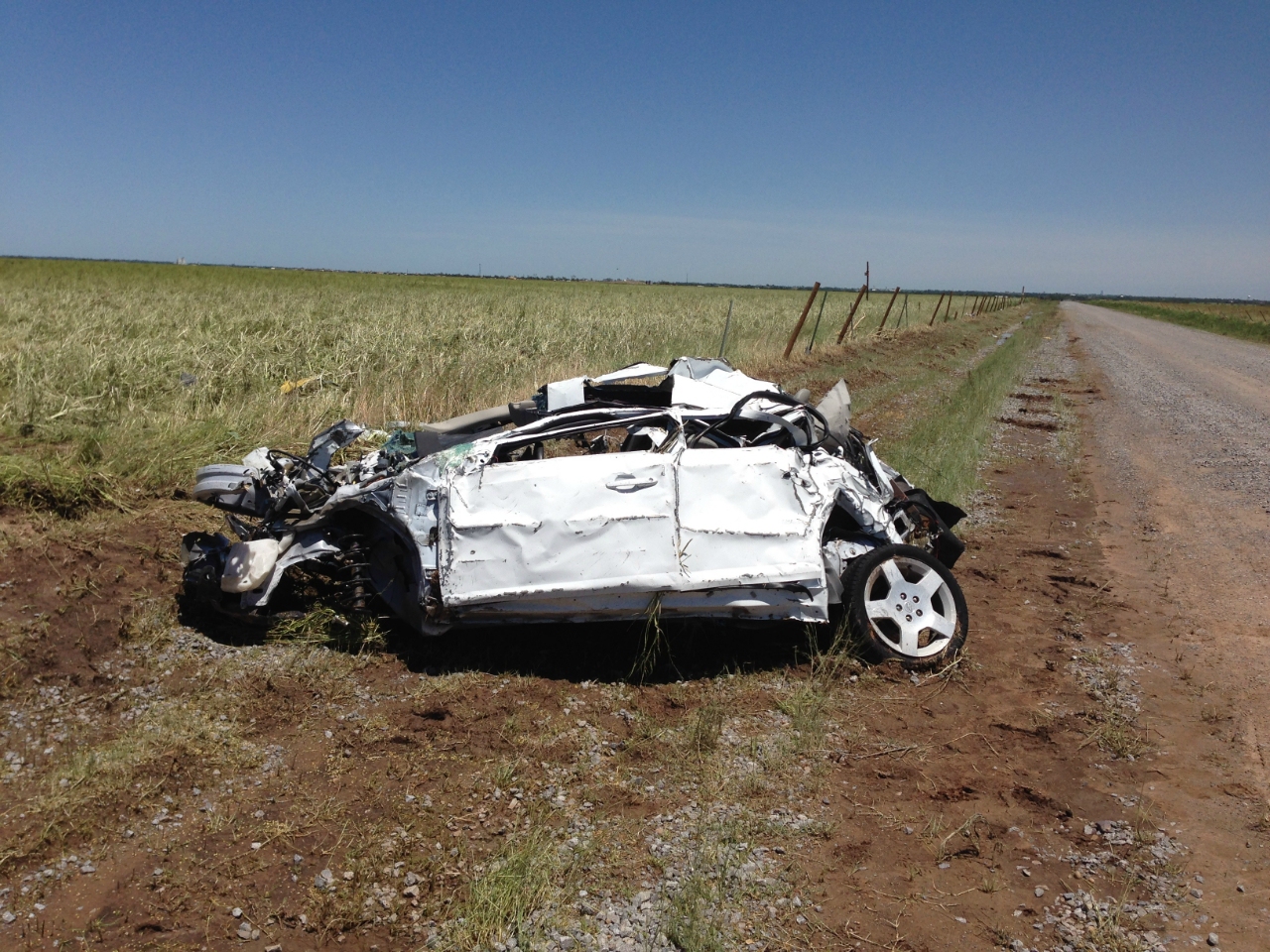 This photo shows a heavily damaged white Chevy Cobalt near the intersection of Reuter Road and S. Radio Road, or 4.8 miles southeast of El Reno, OK. Three storm chasers were killed when this vehicle was hit by one of sub-vortices within the larger circulation of the El Reno tornado. Credit: National Weather Service.