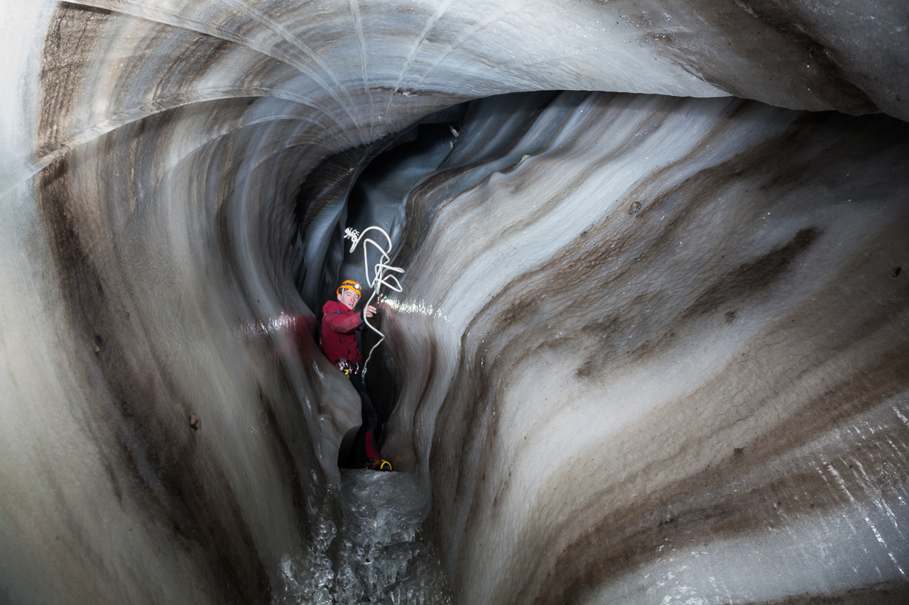 Researchers must ascend and descend frozen waterfalls within the englacial channels. Here, glaciologist Stephen Jennings throws a rope to researchers below. Credit: Ethan Welty.
