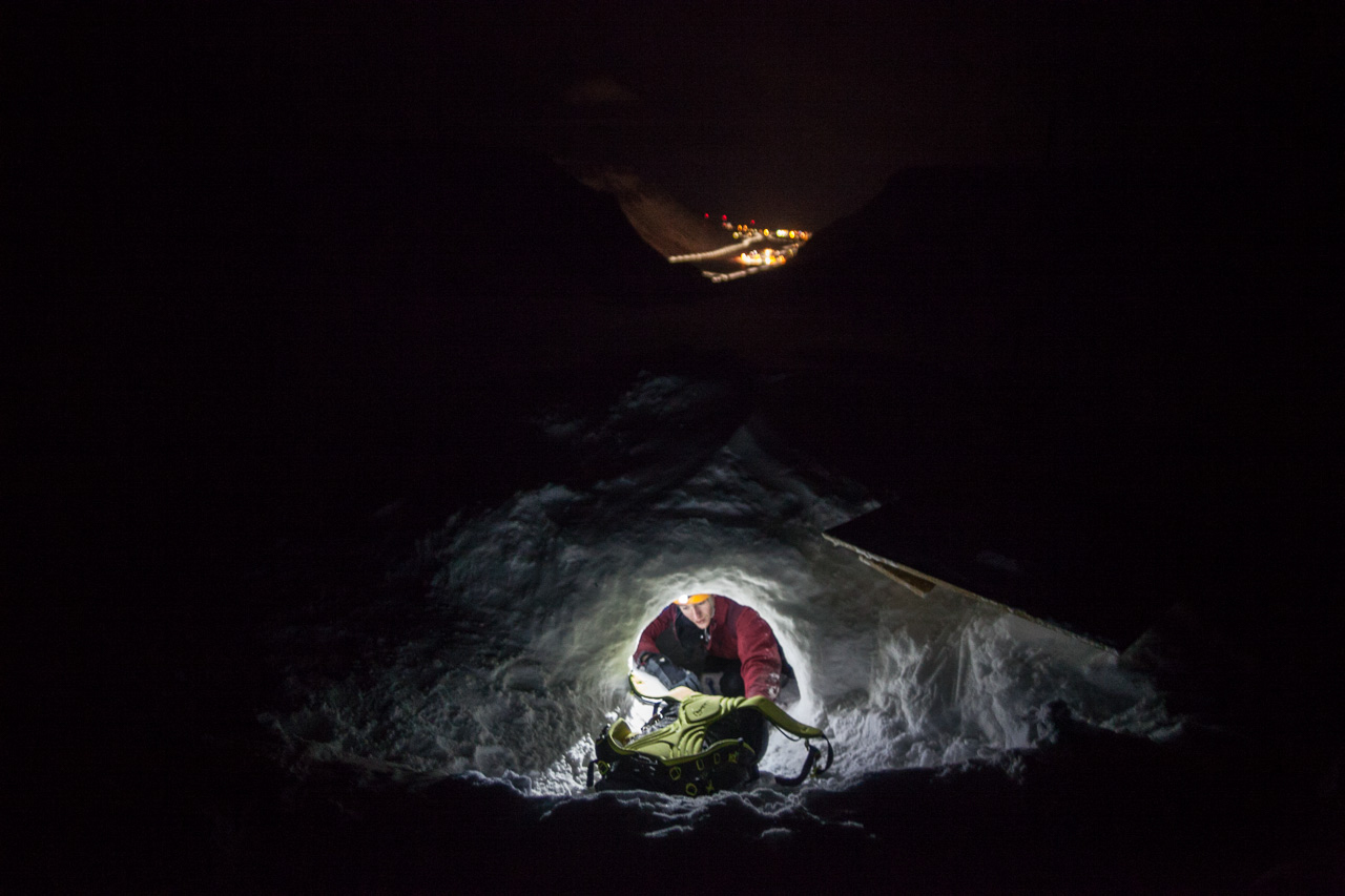 The lights of Longyearbyen are visible as researcher Stephen Jennings appears from at the entrance to this glacial cave system. Most of the team’s work is done during winter months, during 24-hour arctic darkness. Credit: Ethan Welty.
